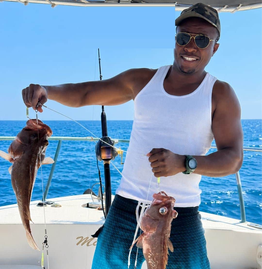 A smiling guest holding up his catch aboard a Royal Marine Tours fishing trip off the Muscat coast