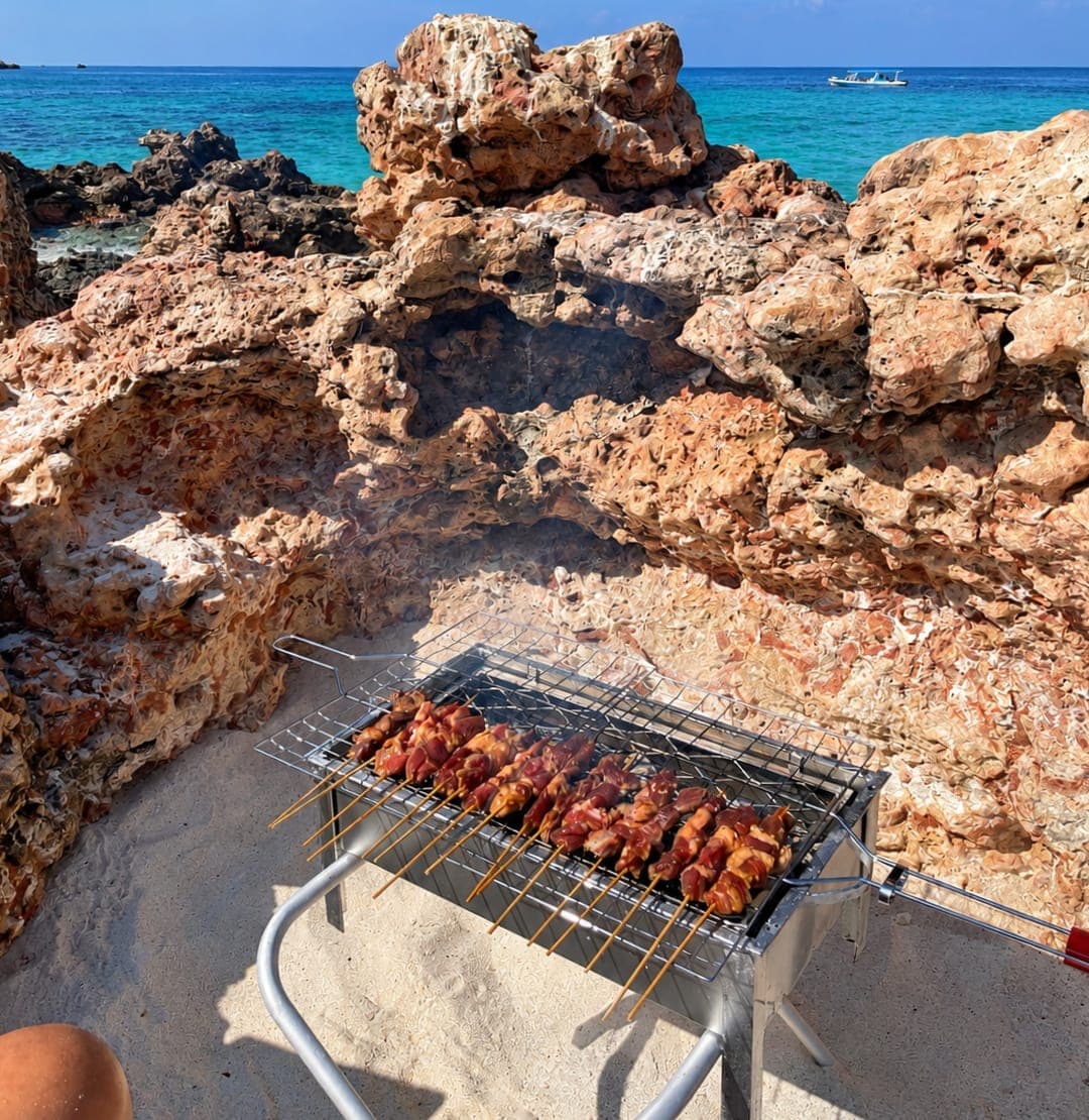 A barbecue grill set up between the rocks on a Daymaniyat island beach