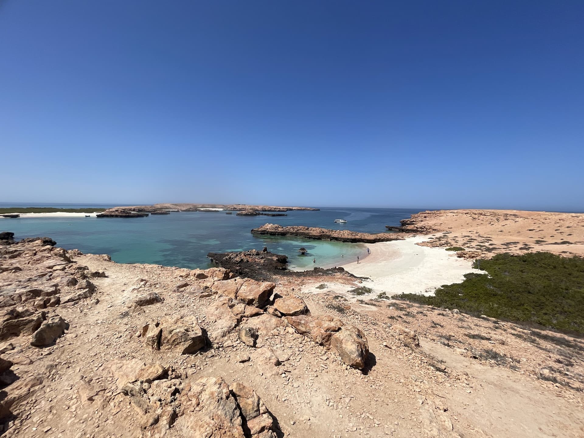 The rocky coastline of a Daymaniyat island under blue sky off Muscat