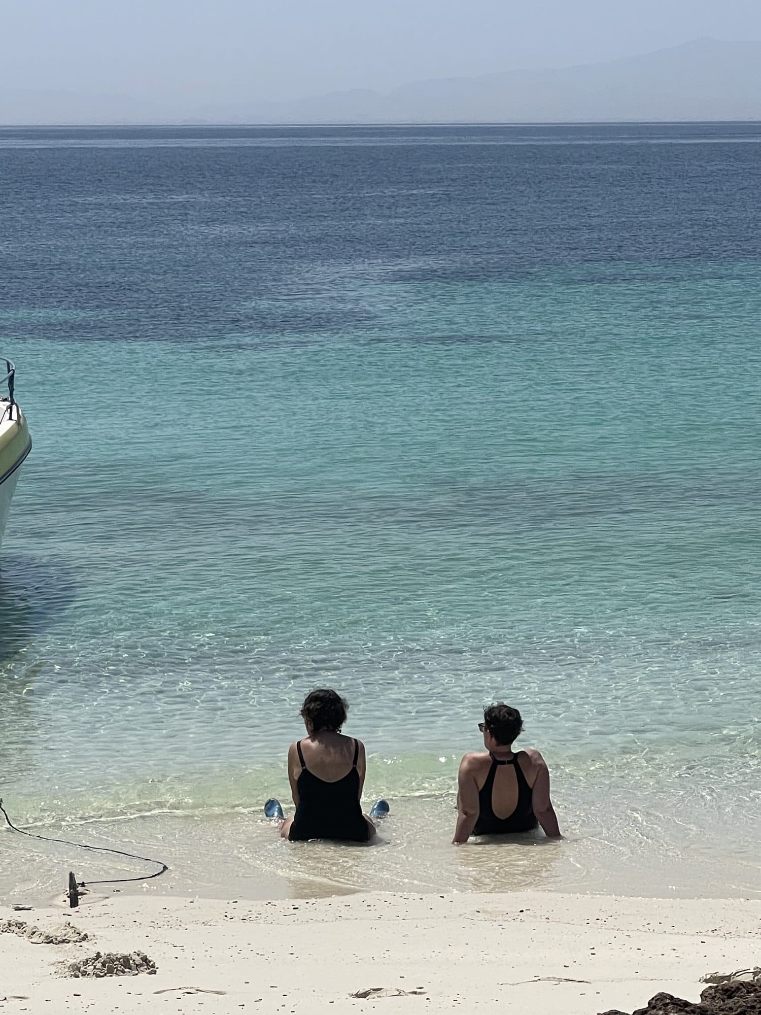Guests sitting in the warm shallow turquoise water at the Daymaniyat Islands