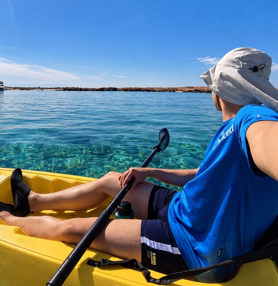 A guest in a yellow kayak looking out over turquoise water at the Daymaniyat Islands