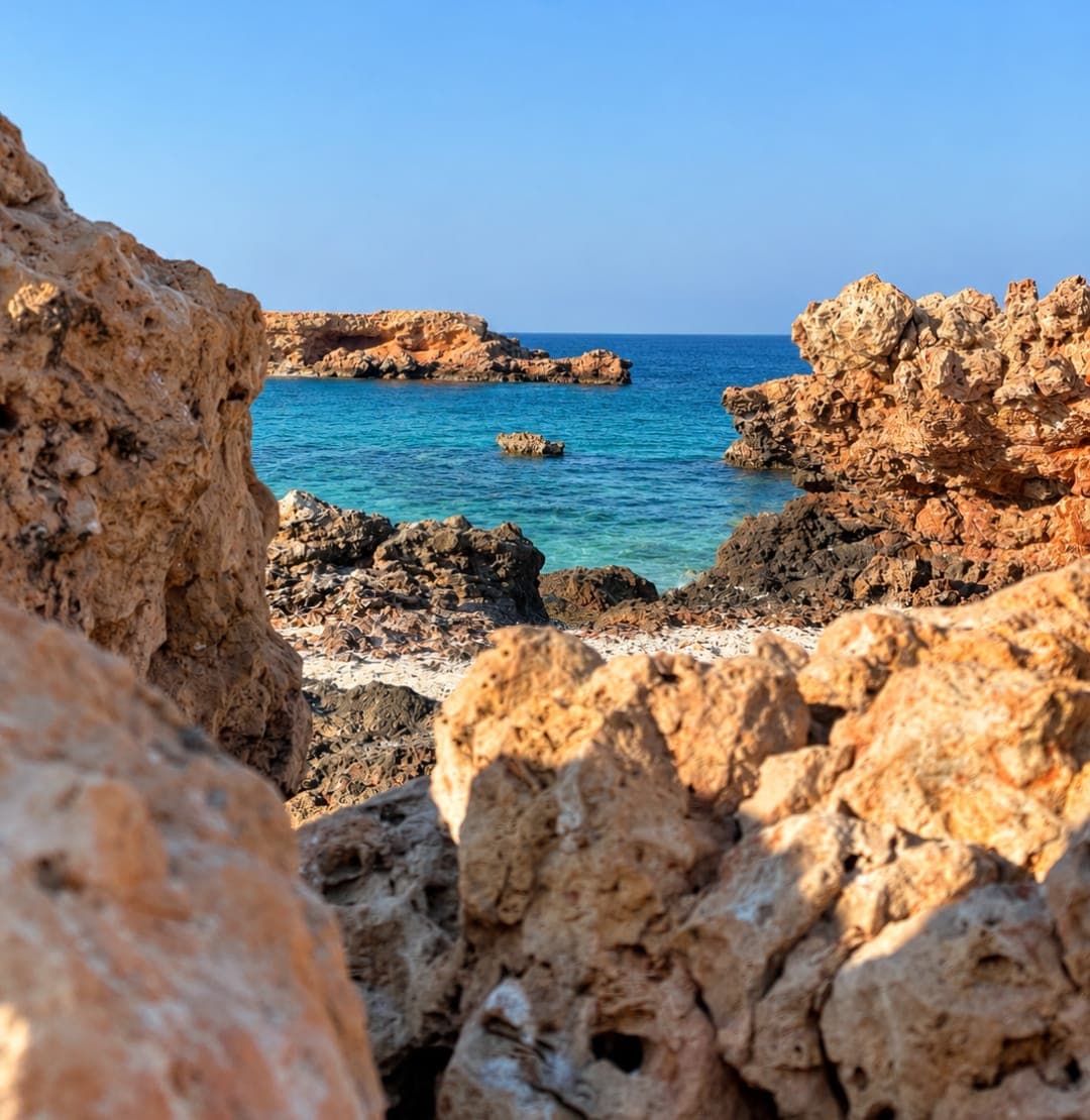 Golden rocks framing turquoise water on the shoreline of a Daymaniyat island