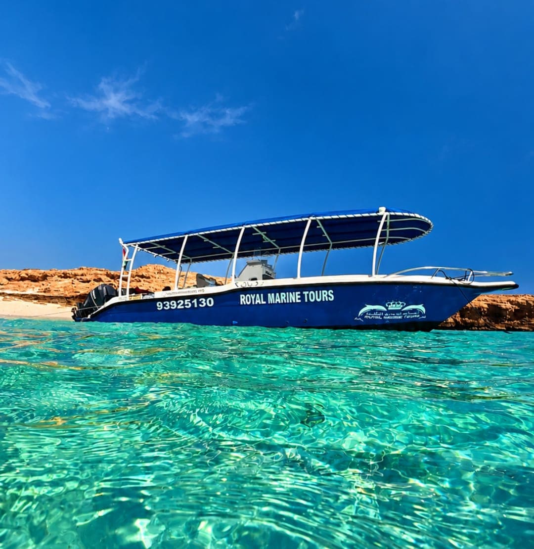 A Royal Marine Tours boat anchored in a clear turquoise lagoon at the Daymaniyat Islands