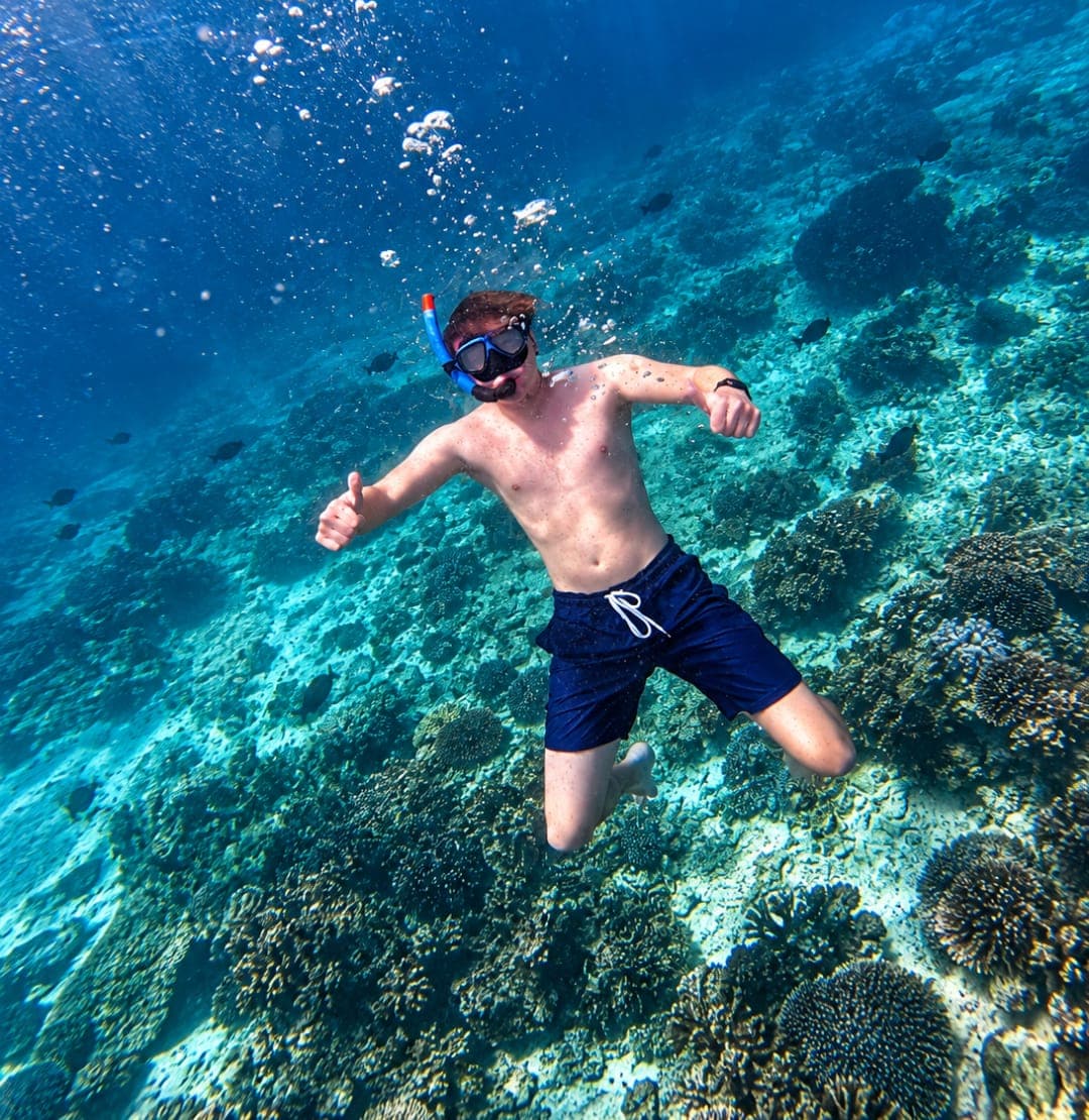 A snorkeller giving a thumbs up underwater over the reef at the Daymaniyat Islands