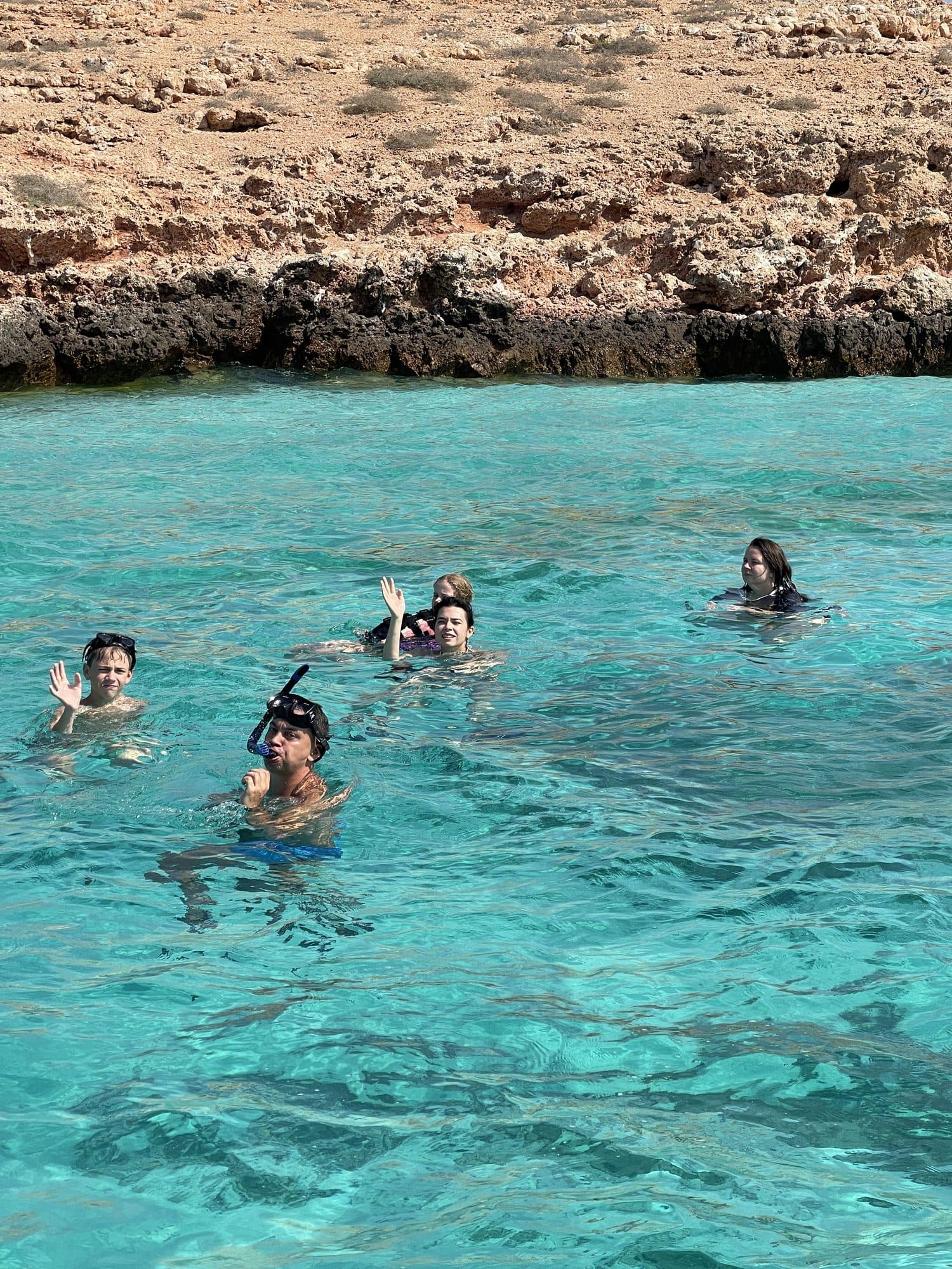 A group snorkelling together in the turquoise water of the Daymaniyat reserve