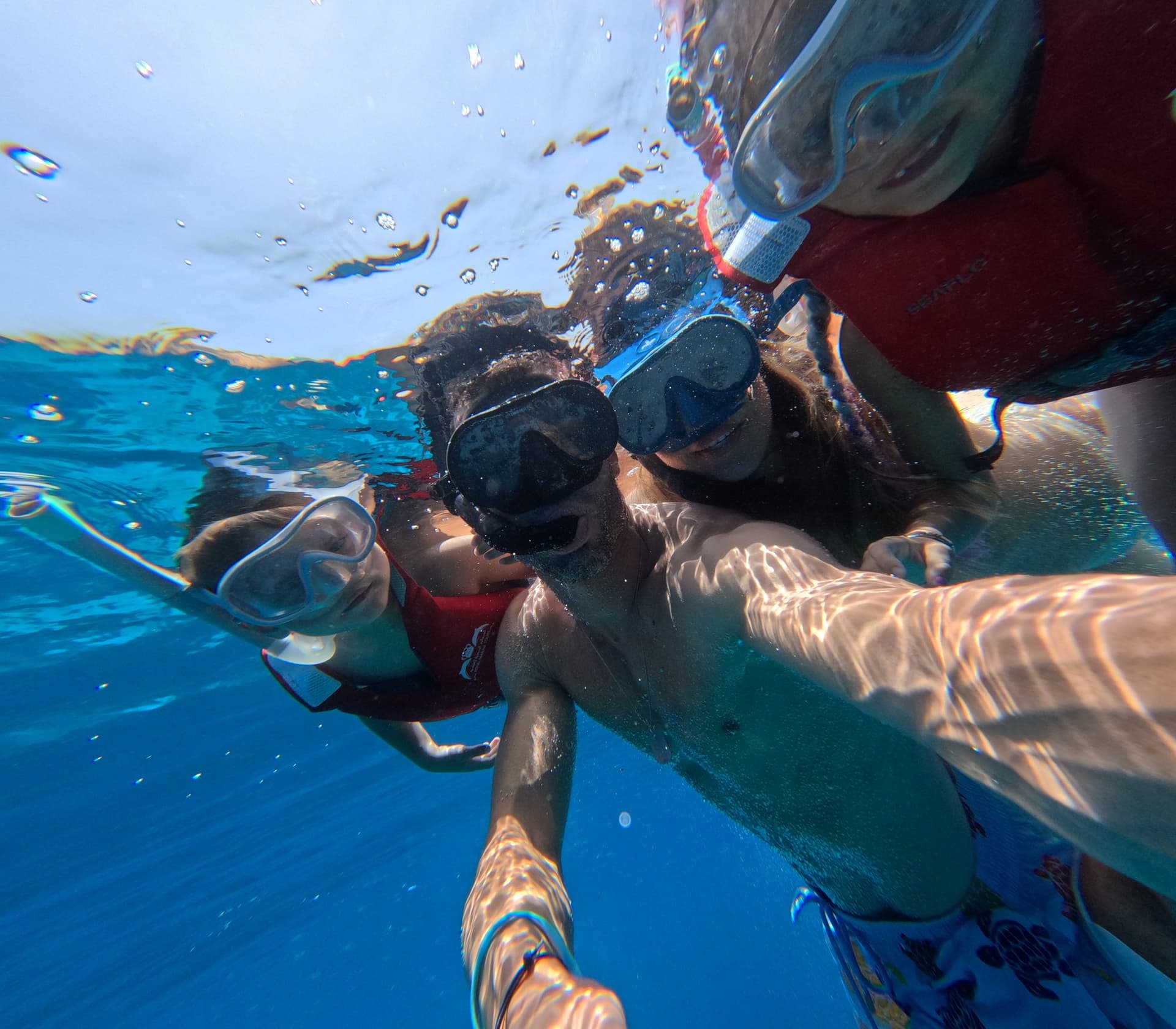 Snorkellers in clear turquoise water beside a Daymaniyat island on a half-day tour from Muscat