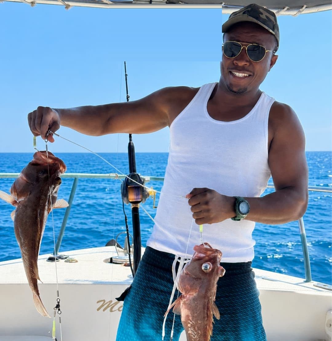 A smiling guest holding up his catch aboard a Royal Marine Tours fishing trip off the Muscat coast